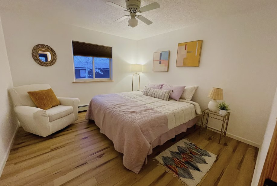 Comfortable guest bedroom with soft pink bedding and an armchair